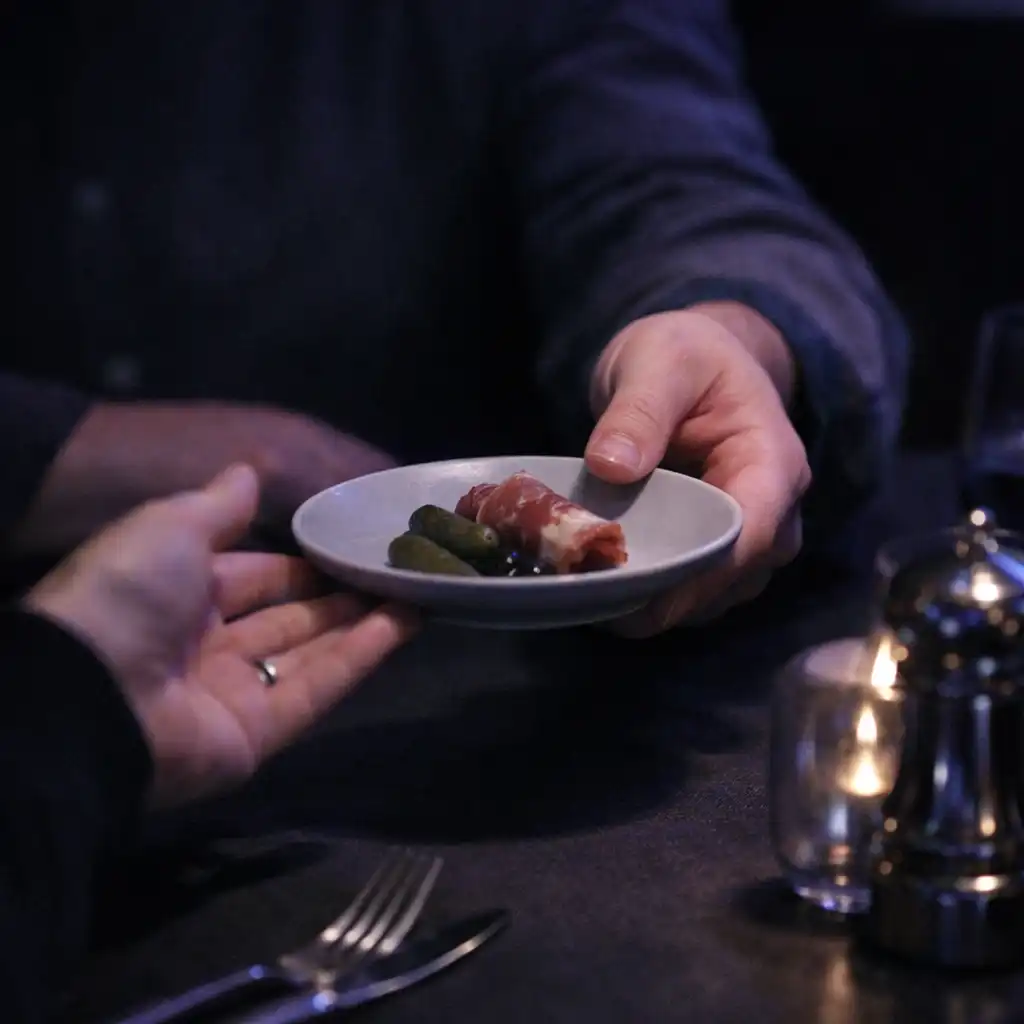 Main adulte faisant passer une petite assiette à table